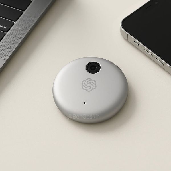 A hockey puck-shaped white device with a camera and the OpenAI logo on it sitting on a desk 