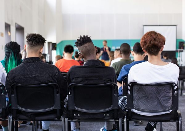 Photo of a classroom taken from the rear of the room, with more than a dozen students shown from the back facing their teacher