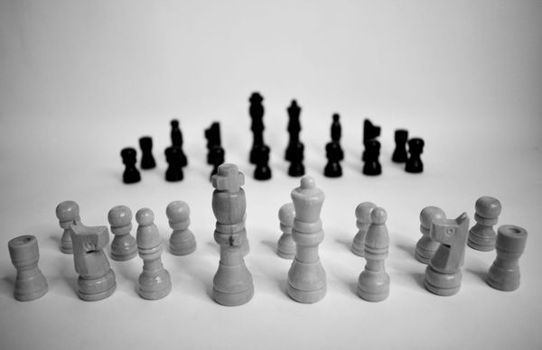 Photo of white chess pieces in the foreground facing black ones in the background