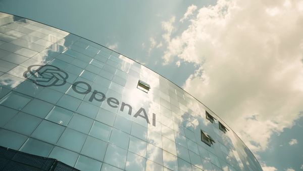 The OpenAI logo and wordmark projected on a curved building with glass windows in Paris in 2024.