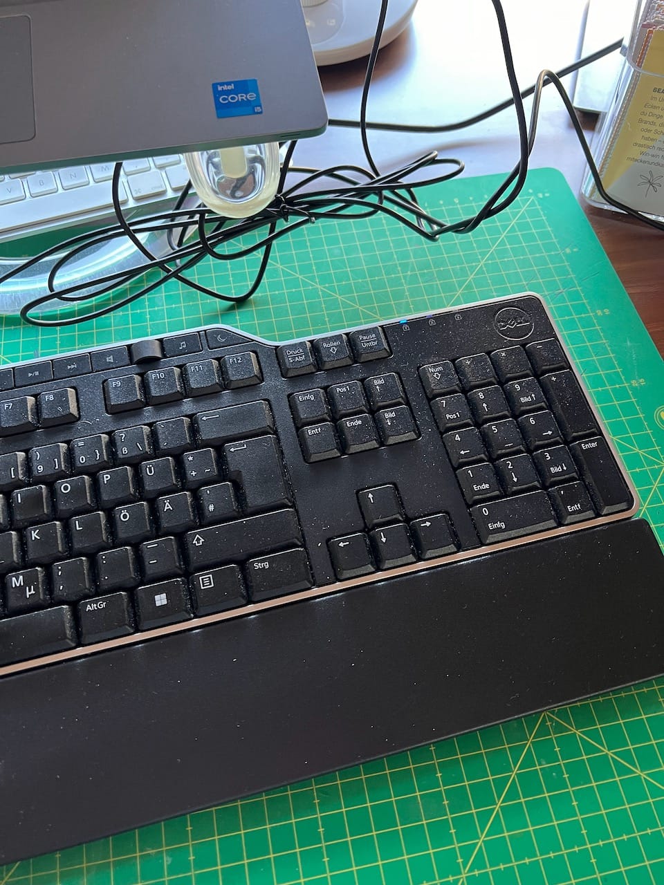eine Tastatur auf einer grünen Schneidematte. Dahinter sind Kabel, die zum Laptop führen. Vom Laptop ist nur eine Ecke zu sehen.