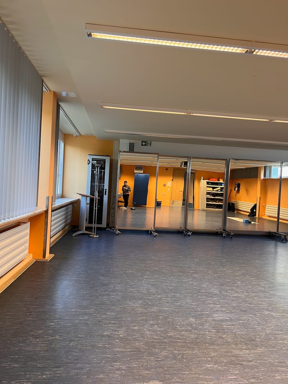 Sportraum mit Spiegeln an einer Wand. Person, die ein Foto von sich macht, ist zu erkennen im Spiegel.