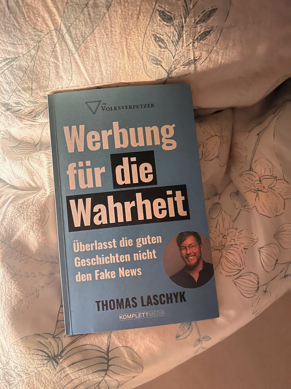 Buch "Werbung für die Wahrheit" von Thomas Laschyk (vom Volksverpetzer) auf Kopfkissen. Dazu sanftes Licht.