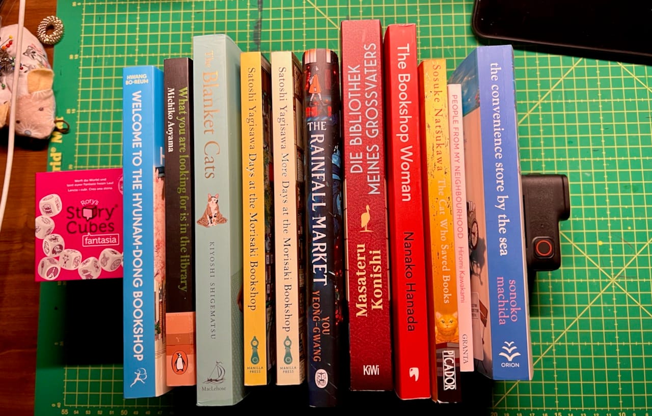 eine Reihe Bücher mit dem Buchrücken nach oben steht auf einem grünen Untergrund. 