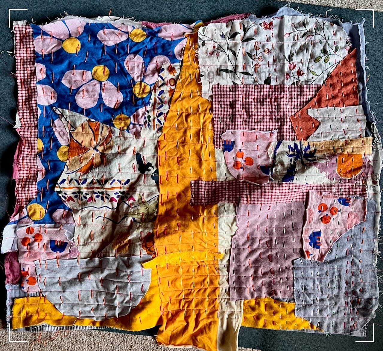 verschiedene bunte Stoffstücke in unterschiedlichen Formen bilden ein Viereck. Die Kanten sind nicht versäubert.