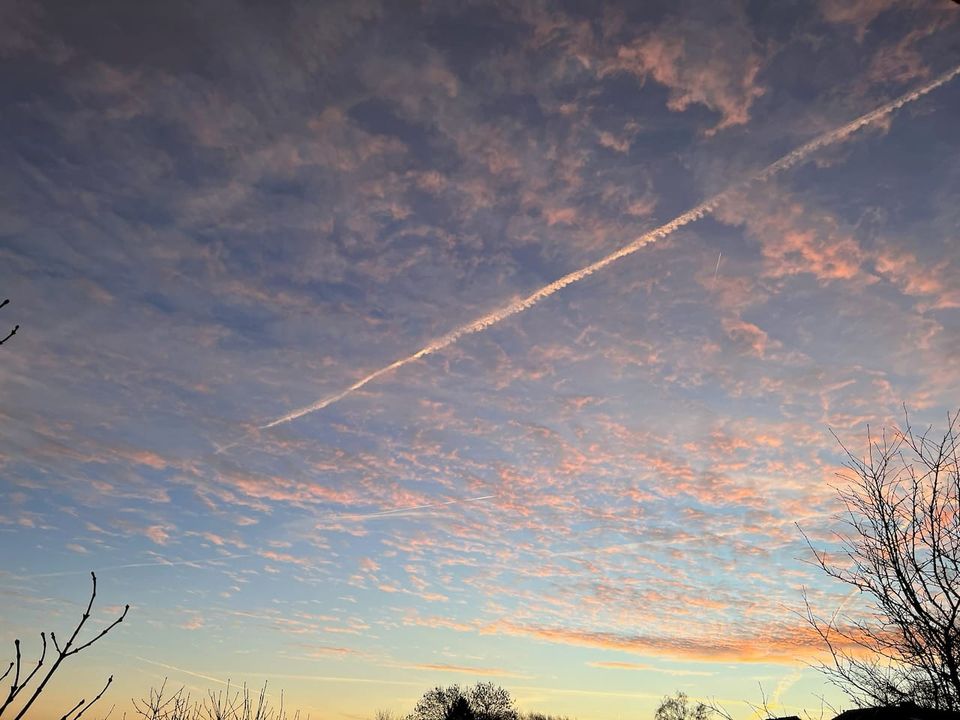 morgendlicher Himmel mit rosa angeleuchteten Wolken und einem Kondensstreifen