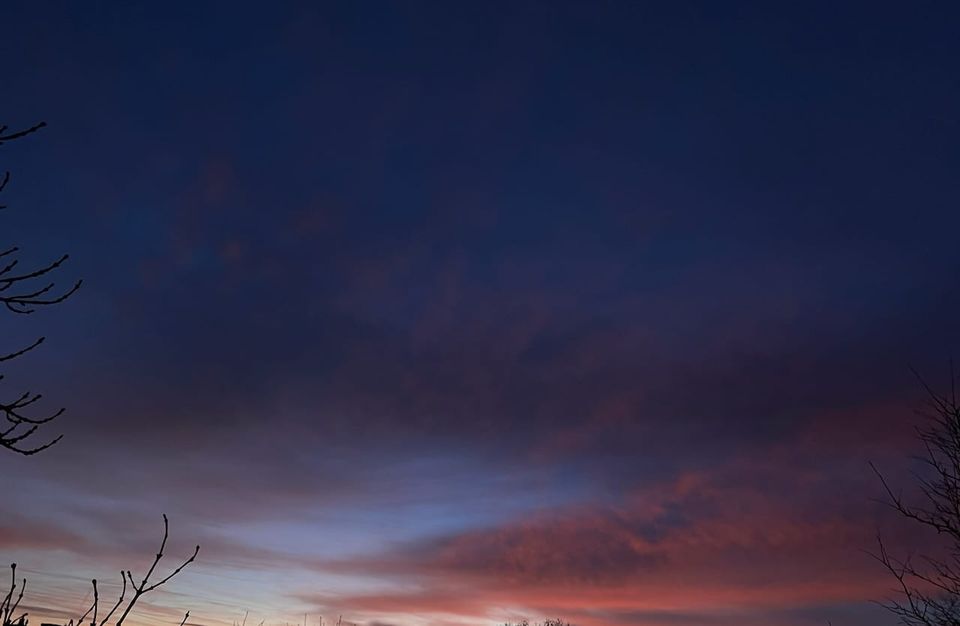 Himmel mit Farbverlauf: oben dunkelblau, wolkenfrei, bis unten mit etwas Wolken, von der aufgehenden Sonne rosa angestrahlt