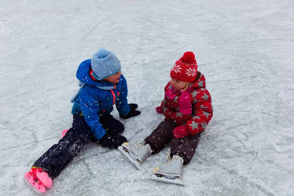Two Small Children sit On Ice At Banff Winter Carnival Alberta Canada