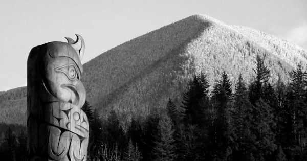 Foto di un totem e di una montagna sullo sfondo.