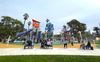 Kids and families playing at a colorful new playground with tall towers and a giant slide at LA's MacArthur Park