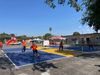 Kids and adults in bright orange shirts playing at two pickleball courts in a large asphalt schoolyard