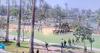 Troops marching through the soccer field of MacArthur Park with a large lake and the skyline of LA in the background