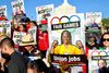 Signs that read Fair Games showing photos of workers are held up by a crowd in front of the LA Coliseum