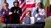 Mayor Karen Bass holds a signed document at a press conference on Venice Beach with an array of flags behind her