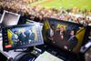 President Donald Trump in a red tie standing with FOX reporters shown on two video screens in the control room of an NFL game