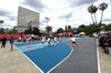 Kids play a pickup game on an outdoor basketball court branded with New Balance logos in a large LA city park