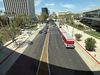 A red rapid Metro bus makes its way down Wilshire Boulevard with the rounded shadow of the new LACMA building seen to the right