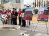 Officials stand in a park in Koreatown with signs that read Koreatown watch party festival
