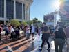 A group of people dance on a large dance floor at LA's Music Center plaza in front of a giant screen