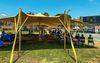 A huge yellow tent stretched out on a grassy area with people watching the World Cup on a large scree 