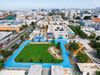 A greened schoolyard with a large grass field and a blue running track at a school in LA's densely populated Westlake neighborhood