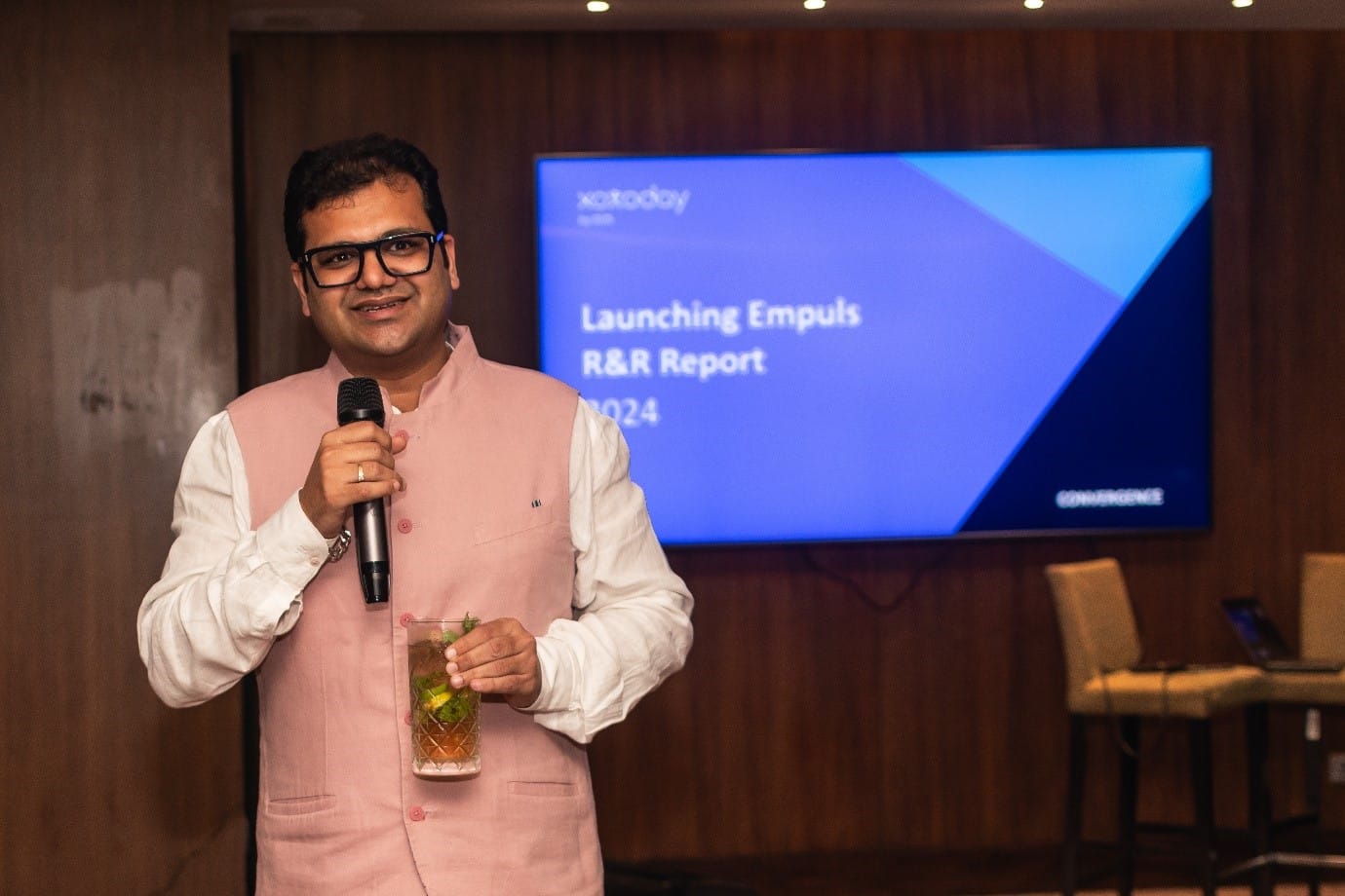 A person holding a microphone and standing in front of a screen