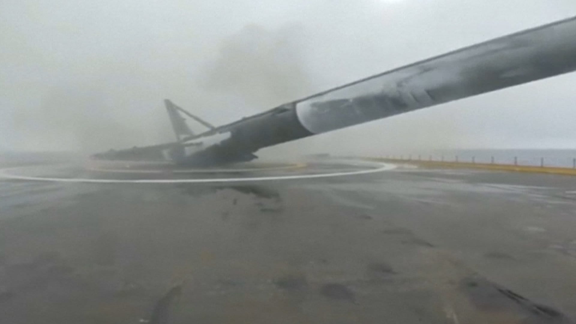 A Falcon 9 rocket falls over after landing on a barge-like automated ship.