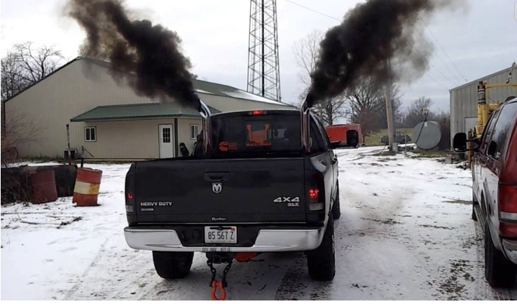 A pick-up truck spews black smoke from vertically raised exhaust pipes "rolls coal." 