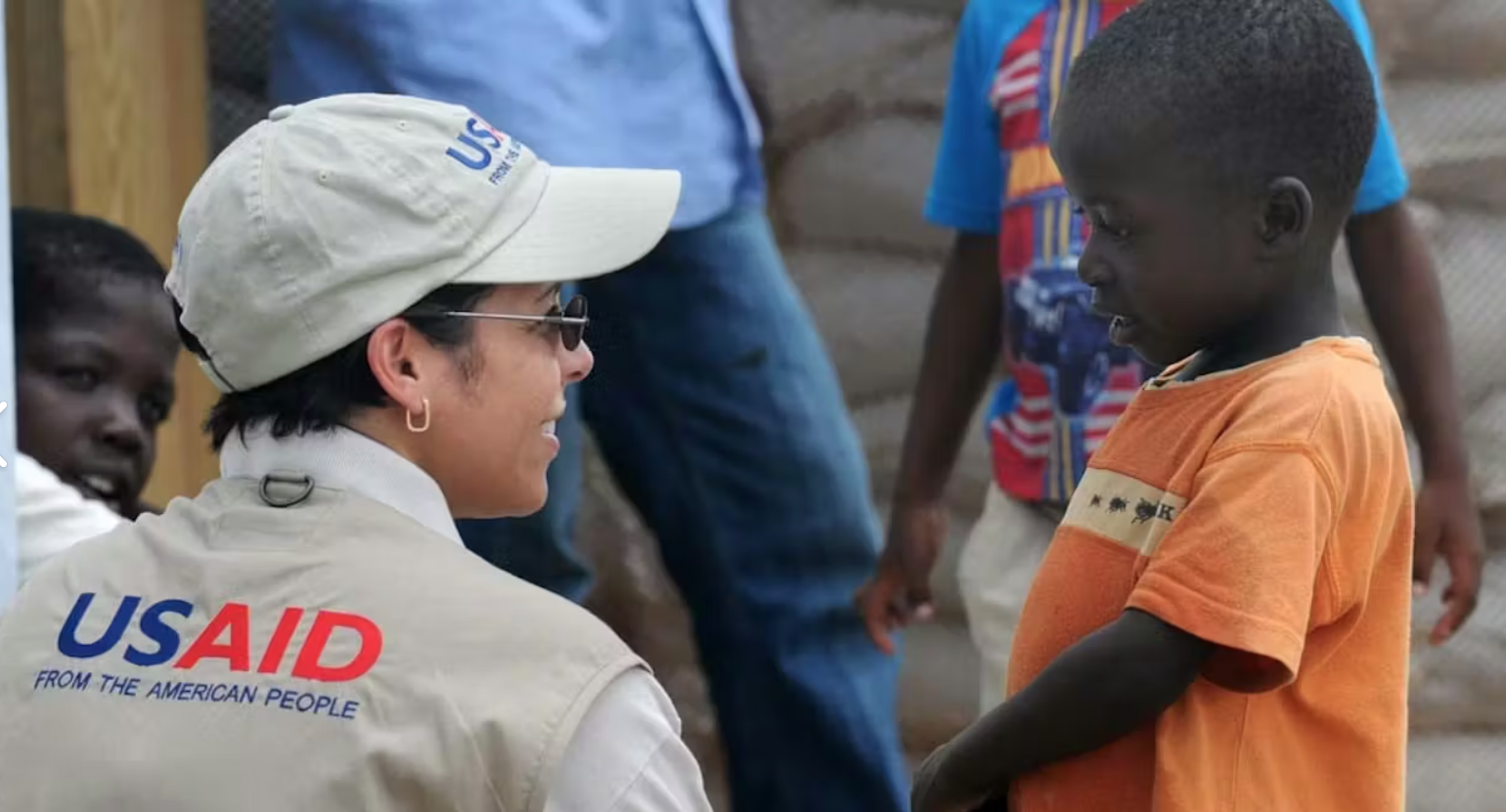 A USAID worker talks with a boy in Kenya.