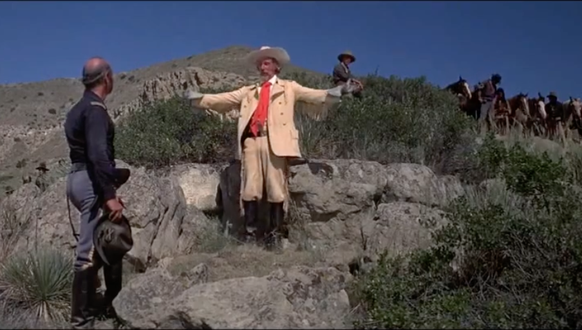 Actor playing Custer outdoors in a buckskin outfit gleefully getting ready to attack.