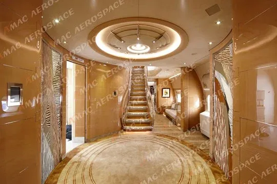 An elevator lobby inside the plane with a staircase and elevator to the second level, all of it decorated in gaudy gold wallpaper and carpets.