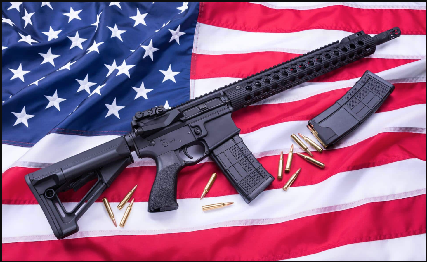 AR-15 plus magazines and bullets resting on American flag.