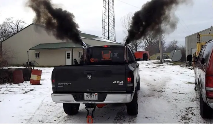 A pick-up truck spews black smoke from vertically raised exhaust pipes "rolls coal." 