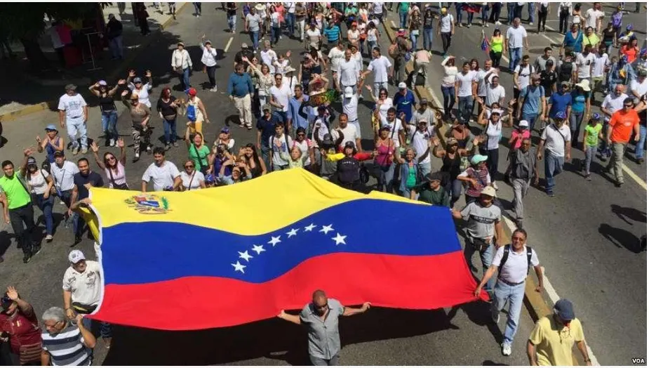 Anti-Maduro protesters in the streets with a huge Venezuelan flag.