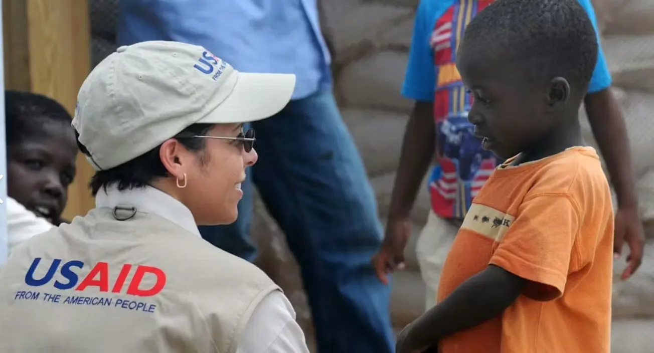A USAID worker talks with a boy in Kenya.