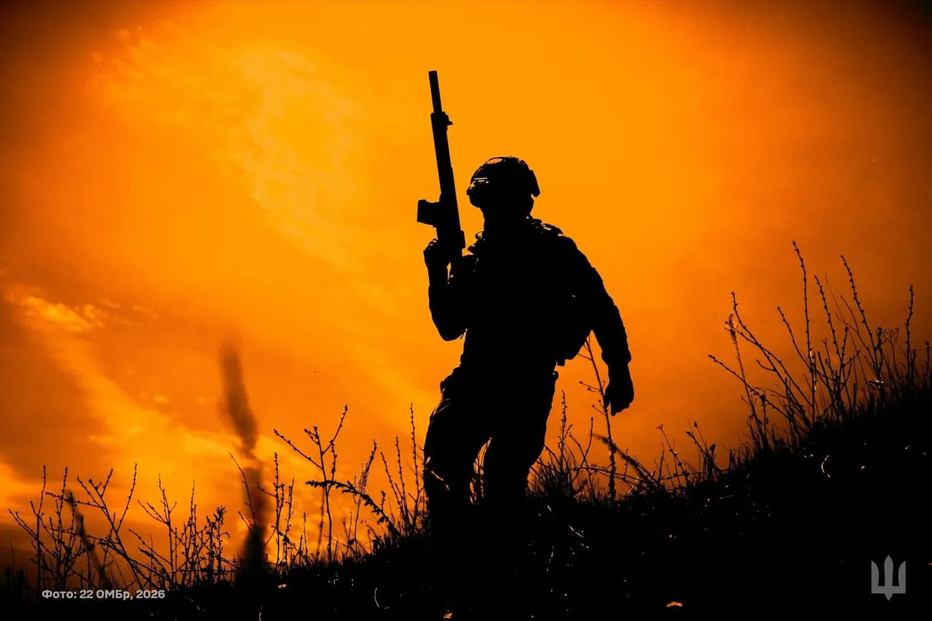 Silhouette of a soldier with a rifle against an orange sunset