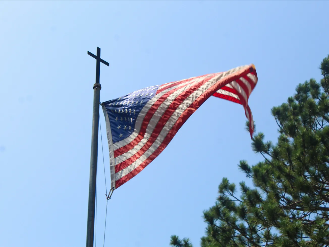 U.S. flag with Christian cross atop the pole.