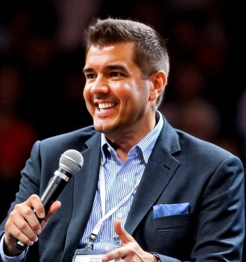 Craig Bowman speaking on a panel, mid-conversation, holding a microphone.