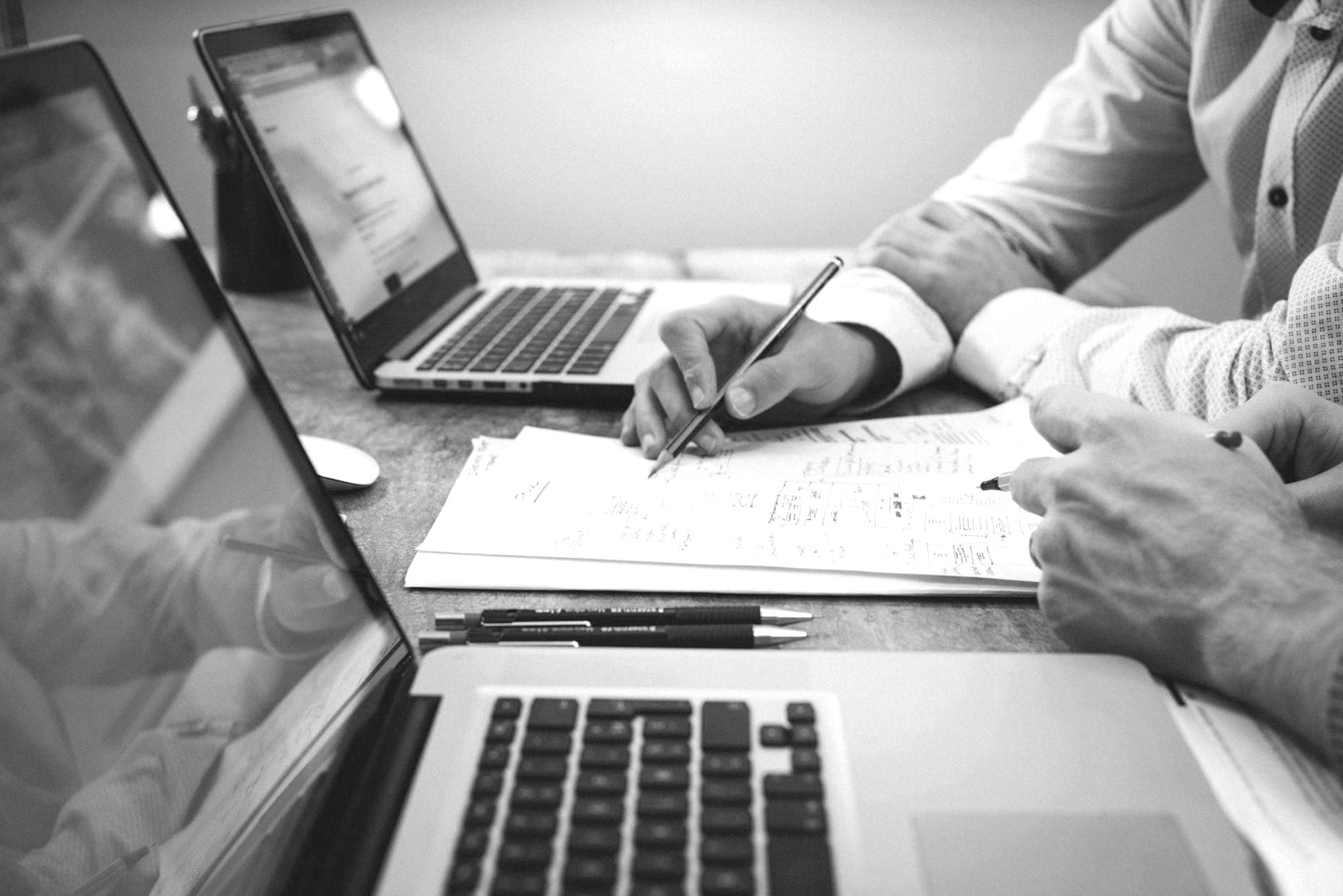 person holding pencil near laptop computer