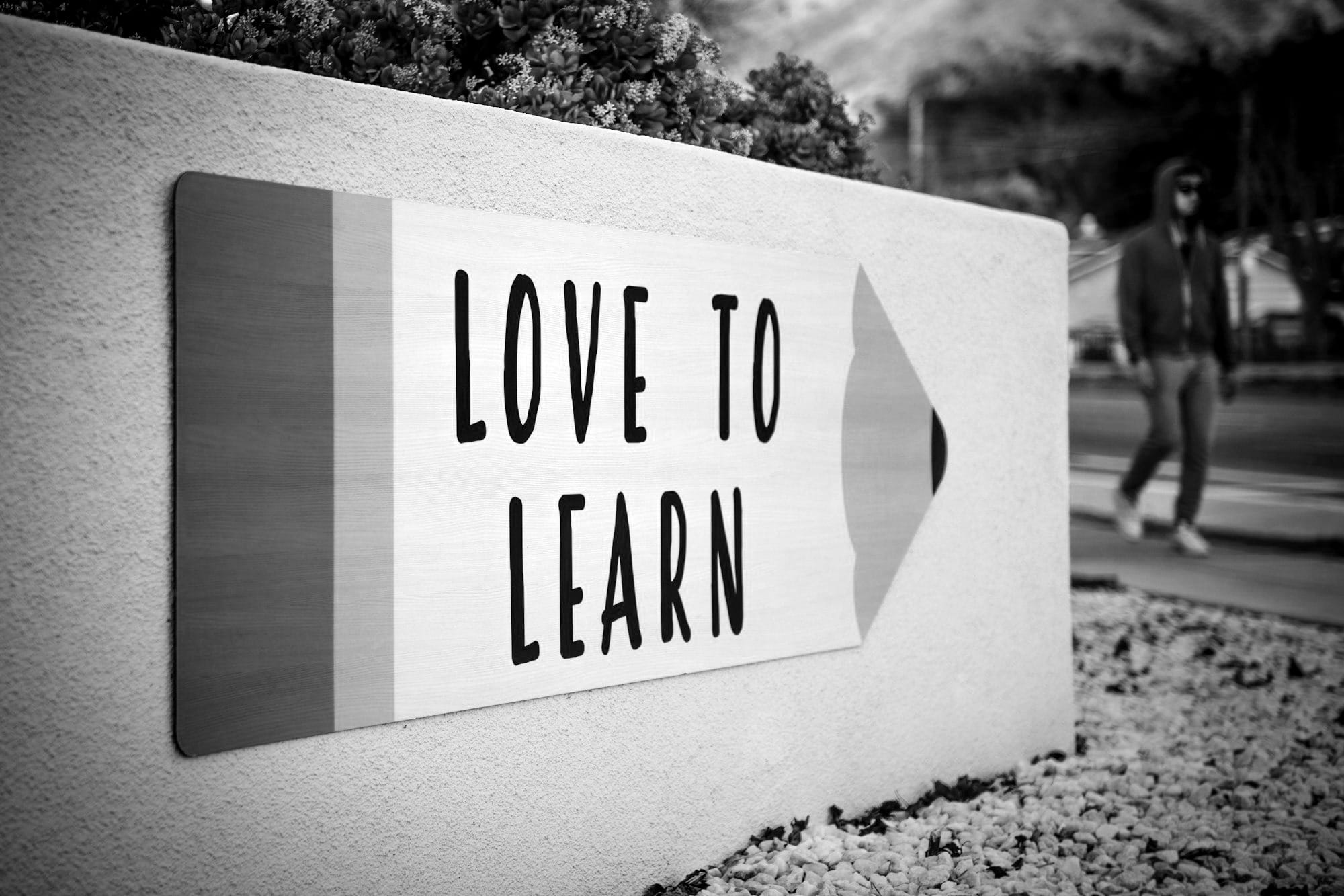 love to learn pencil signage on wall near walking man