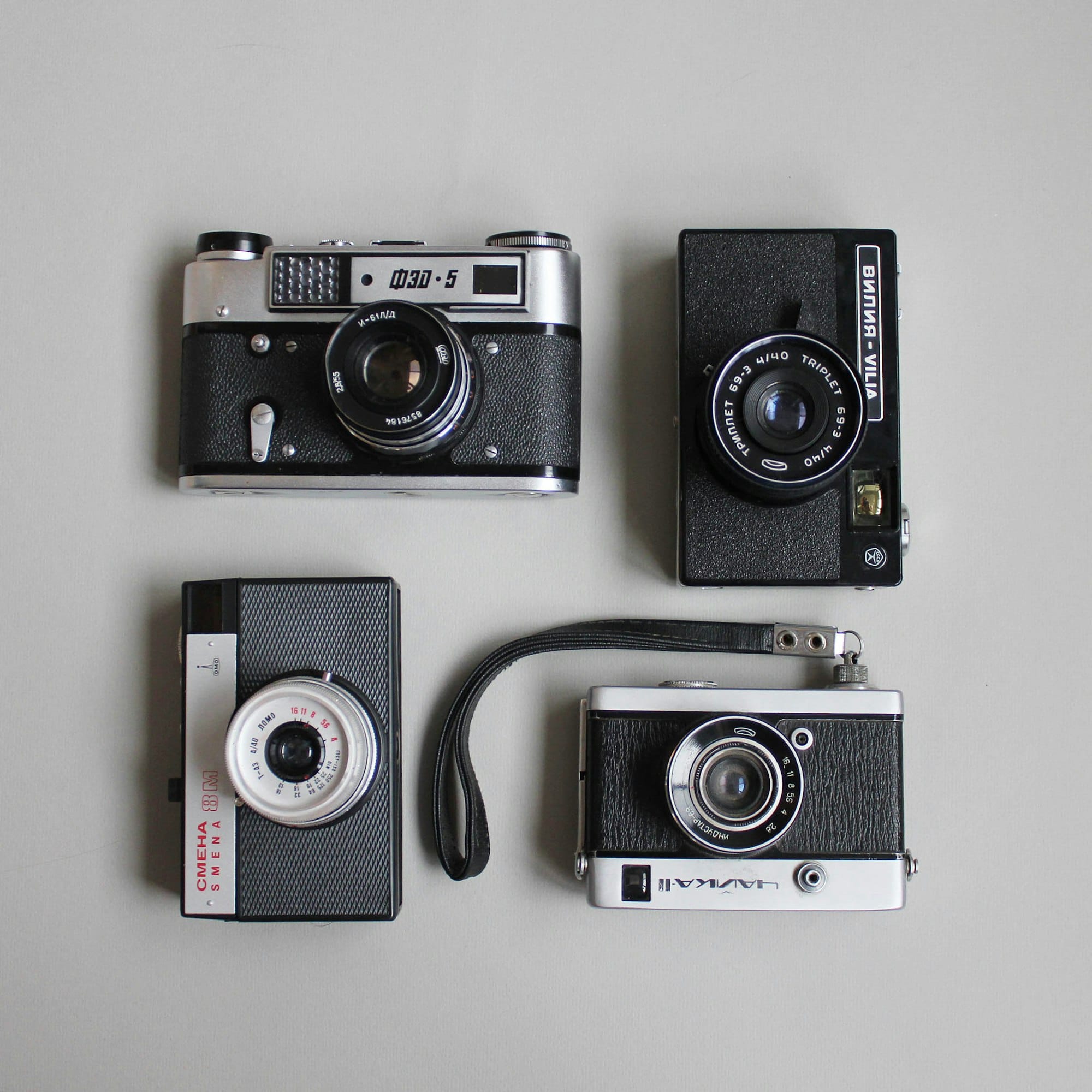 Four vintage analogue cameras arranged on neutral ground