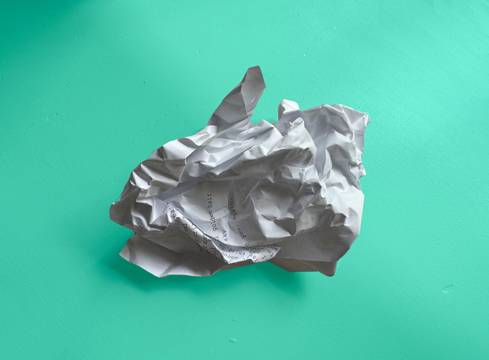 A balled-up piece of paper lies on a teal background.