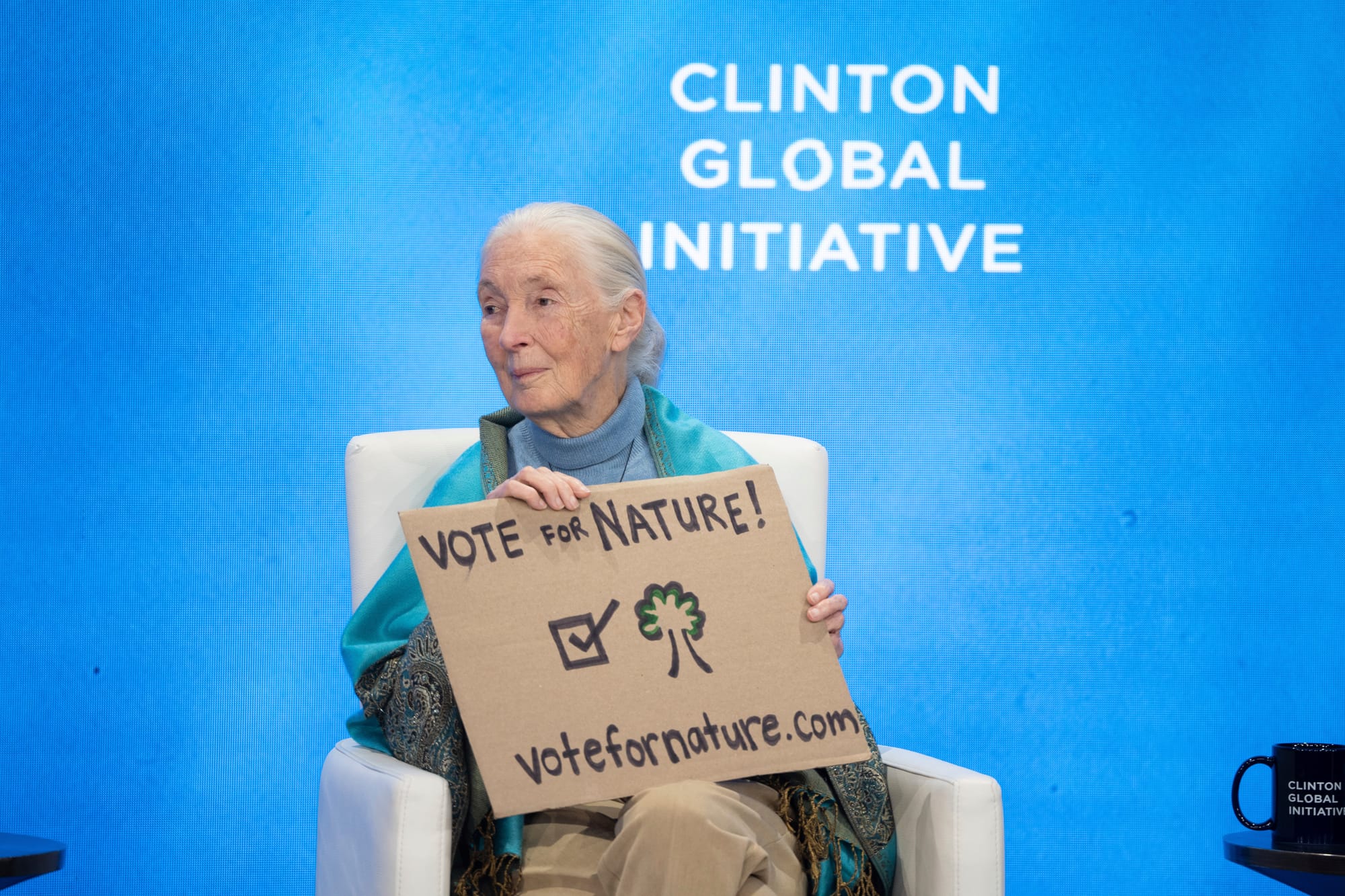 Jane Goodall holds a cardboard sign that says "Vote for Nature"