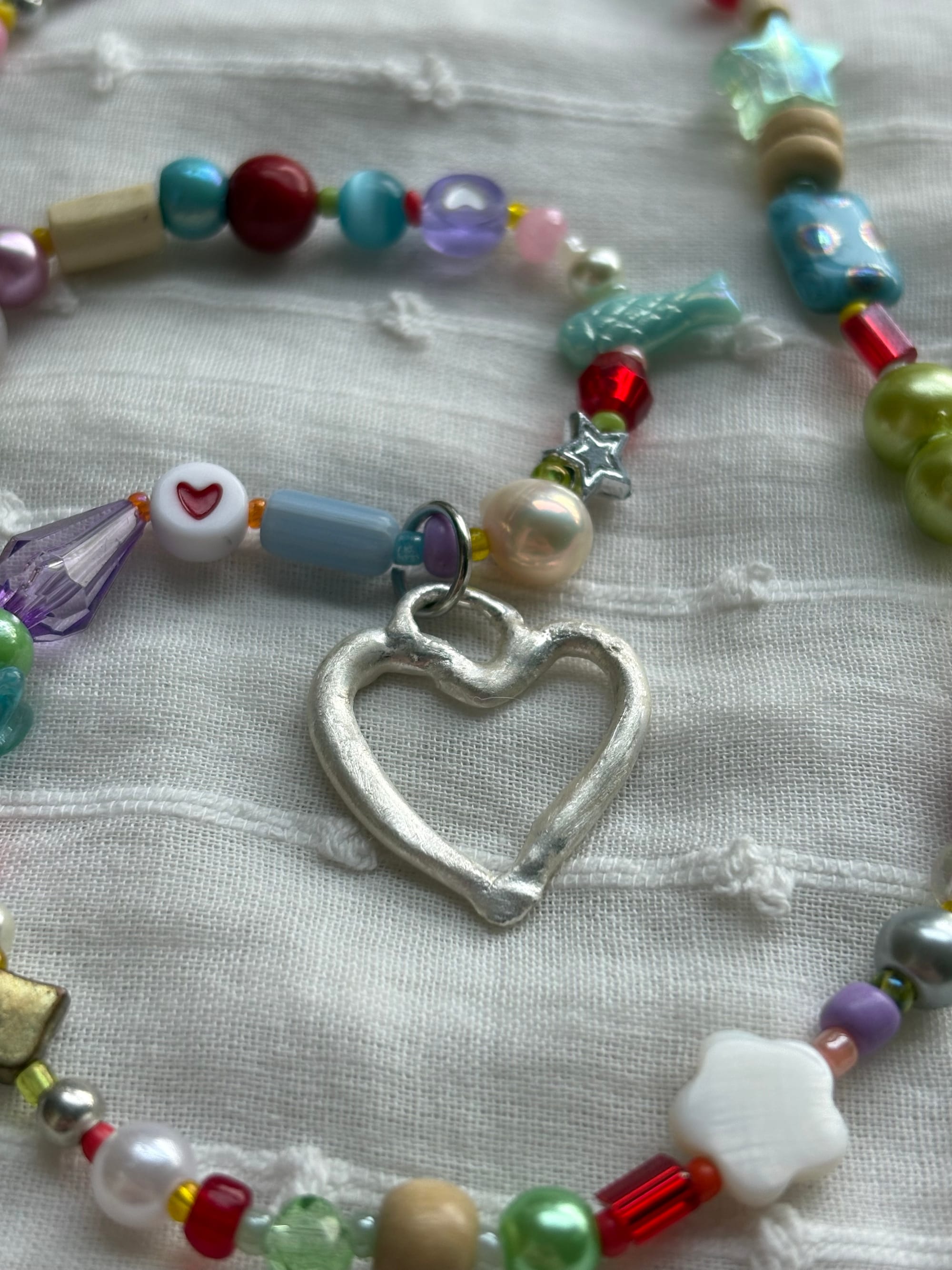 Beaded jewelry with a heart-shaped silver clay pendant.