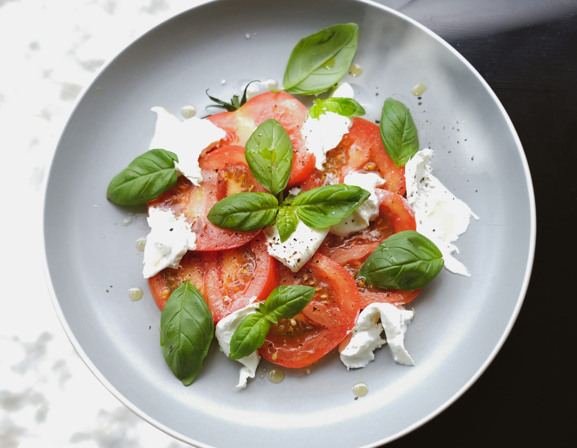 Plate with tomato, mozzarella and basil arranged.