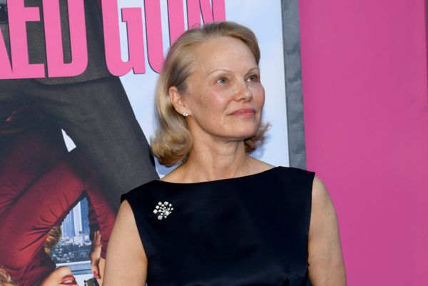 Pamela Anderson, with a flicked-out blonde bob and little makeup, wears a navy top with a jewelled brooch.