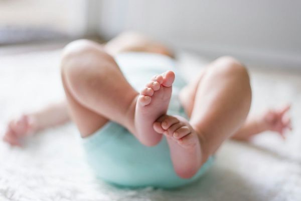 A soft-focus image of a baby lying down. Only its feet are in focus. 