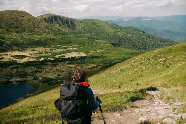 A hiker looking across grass-covered mountains.