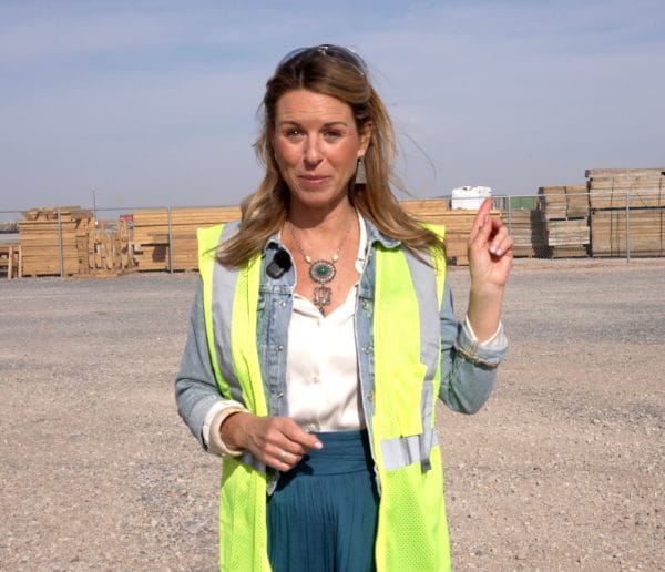 Woman in safety vest standing in front of a wood yard