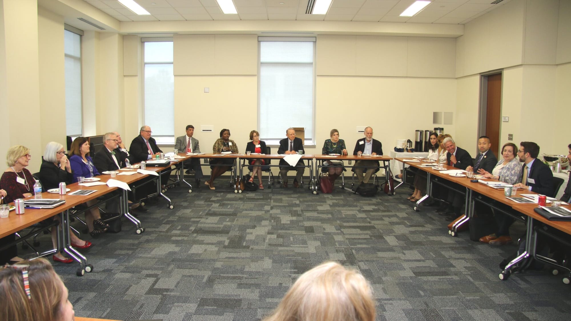A meeting of the Maryland Regional Direct Services Collaborative [image description: A large group of people sit at tables arranged in a square in a community college meeting room.]